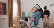 © ABCreative - A little girl helps her parents unpack boxes. She discovers her favorite toy, a teddy bear, and hugs it tightly as her mom and dad smile at the sweet moment.