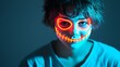 © thanarak - Close up portrait of a teenage boy with vibrant neon face paint glowing under mysterious UV lighting against a dark background