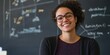© Iryna - A woman with glasses is smiling at the camera in front of a blackboard with equations on it