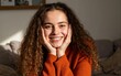 © Yuudaishin - Smiling Woman with Curly Brown Hair Wearing Orange Sweater in Cozy Indoor Setting – Natural Beauty and Warm Expression