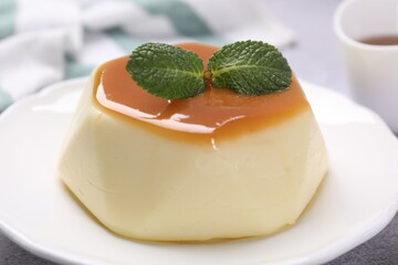 Wall Mural - delicious pudding with caramel sauce and mint on light table, closeup