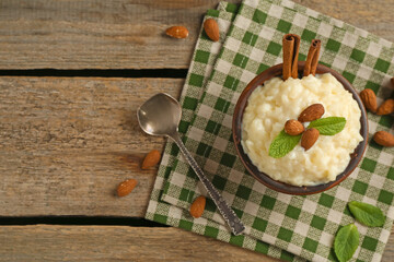 Wall Mural - delicious rice pudding with almonds, mint and cinnamon sticks served on wooden table, flat lay. spac