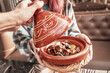 © EdNurg - Close up of a traditional Moroccan tajine with lamb, dried fruits and spices being uncovered by a waiter in a restaurant