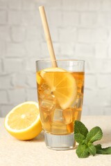 Wall Mural - refreshing iced tea with drinking straw, mint and slices of lemon on light textured table against gr