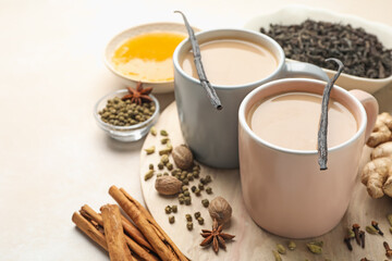 Wall Mural - aromatic masala tea in cups, spices, honey and dry leaves on light grey table, closeup. space for te