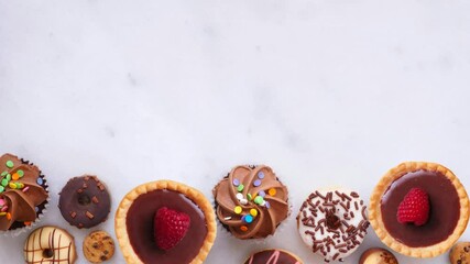 Leinwandbilder - dessert bottom border with n assortment of sweets. overhead view, stop motion video on a dark stone 