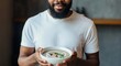 © Postmodern Studio - African male adult holding mushroom soup bowl with parsley garnish