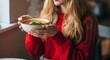 © Postmodern Studio - Young caucasian female enjoying warm soup in cozy indoor setting