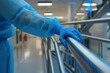 © Baba Images - Person cleaning a hospital railing with blue gloves