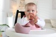 © New Africa - Cute little baby eating with spoon on feeding chair at home