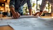 © Chandlerlikes - An architect collaborating with clients over rolled architectural plans.