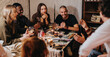 © qunica.com - A close-knit group of friends shares laughter and conversations around a table, enjoying food and drinks during a cozy indoor gathering, fostering warmth and companionship.