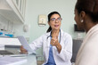 © fizkes - Friendly engaged middle aged elder doctor giving consultation to African patient, talking to young woman in office, holding paper medical report, history, giving prescription, explaining treatment