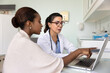 © fizkes - African patient and mature female doctor reviewing examination results on laptop, pointing at monitor, discussing online medical report. Young woman consulting therapist