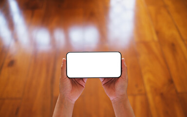 Wall Mural - top view mockup image of a woman holding mobile phone with blank desktop screen with wooden floor ba