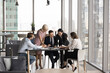 © fizkes - Group of five businesspeople engaged in business meeting in modern office, focusing on documents around table, discussing business strategy, make financial decision, analyzing or reviewing information