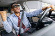 © Home-stock - Overjoyed African American guy in sunglasses dancing in car, listening music and singing while sitting at drivers seat