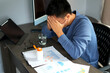 © S K Tu Mai - A young asian manager is taking medicine while sitting in front of laptop at office, looking for treatment against coronavirus, cold or flu and has been suffering headache due to heavy work load.