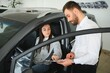 © Serhii - Car seller showing customer brand new car and talking about its performances