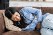 © kucherav - Woman suffering from stomach pain at home