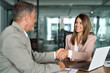 © insta_photos - Happy professional mature leaders businessman and businesswoman in suits shake hands sitting at table having partnership business contract agreement with handshake at corporate meeting in office.