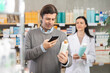 © JackF - Man scans QR code on medicated shampoo label. Female pharmacist offers to choose the right shampoo