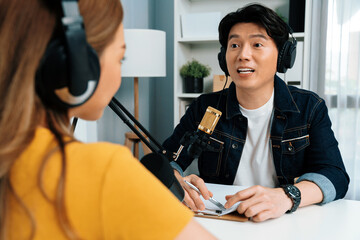 Smiling radio influencer host wearing headphone interviewing woman speaker sharing information to listeners on social media online website live streaming channel at morning at studio record. Infobahn.