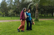 © FABIAN PONCE GARCIA - Two senior women walking and smiling in green park