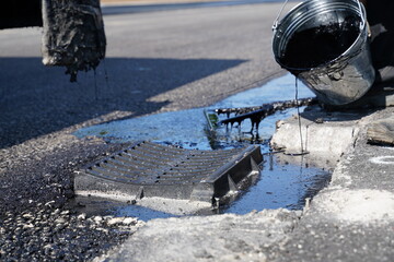 Fototapete - Pouring liquid bitumen onto fresh asphalt around drainage cover, ensuring watertight seal at highway road construction site
