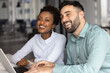 © fizkes - Diverse couple of cheerful young employees meeting at laptop in office, looking away, smiling, laughing, talking to coworkers off screen, having fun. Happy colleagues working at pc together