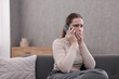 © New Africa - Depressed woman calling hotline for mental health help on sofa at home