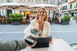 © Martí Rosselló - Woman Making Contactless Payment with Phone at Outdoor Café - Smiling woman using smartphone to pay at a terrace table with coffee and tablet in city - Payment Concept