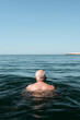 © Amy - Rear view of man floating in sea with head above water under clear blue sky