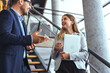 © Dragana Gordic - Two Business People Discussing on the Staircase in a Modern Office Setting