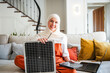 © Westend61 - Muslim woman in a living room holding a solar battery and smiling