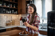 © Migma_Agency - Smiling woman enjoying breakfast and using smartphone in modern kitchen