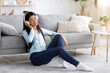 © Prostock-studio - Relaxing Playlist. Young Asian Girl Listening Music In Wireless Headphones At Home, Sitting With Closed Eyes On Floor In Living Room, Free Space