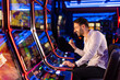 © Dragana Gordic - Excited Man Winning on Slot Machine in Vibrant Casino Setting