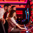 © Dragana Gordic - Group of Friends Enjoying Slot Machines in a Modern Casino Setting