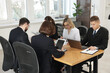 © New Africa - Coworkers with different devices working together at wooden table in office