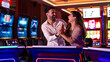 © Dragana Gordic - Happy Couple Celebrating Together in a Casino Playing Slot Machines