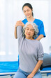 © ArLawKa - Elderly woman receives medical services from home care nurse while performing muscle strengthening exercises.