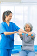 © ArLawKa - Elderly woman receives medical services from home care nurse while performing muscle strengthening exercises.