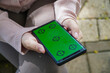 © Fransisca - Close Up of Hands Holding a Green Screen Mobile Phone Device with Chroma Key in Sunny Outdoor Light