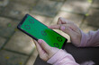 © Fransisca - Hands Holding a Smartphone with Green Screen for Compositing with Mockup Targets outdoors in Natural Lighting