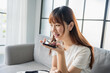© Charlie's - Asian woman holding smartphone near mouth talking with friend