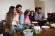 © Drobot Dean - A diverse group of young adult friends in their late 20s, gathered around a Black woman in her 20s, who's wearing a tiara, as she cuts into her birthday cake while they celebrate her birthday, indoors