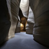 A breathtaking view inside a narrow sandstone canyon reveals smooth, sculpted walls and a soft light illuminating the intricate details of the natural rock formations.