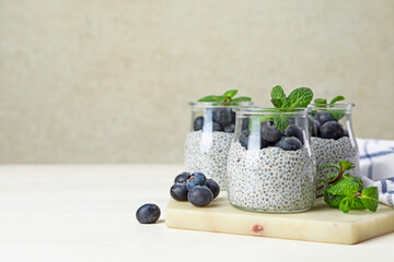 Wall Mural - delicious chia pudding with blueberries and mint in glasses on light table, space for text