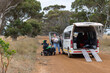 © Austockphoto - Mother transferring adult son from van to wheelchair on a gravel access road in country